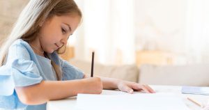 یک دختر کودک درحال نوشتن مشق های مدرسه